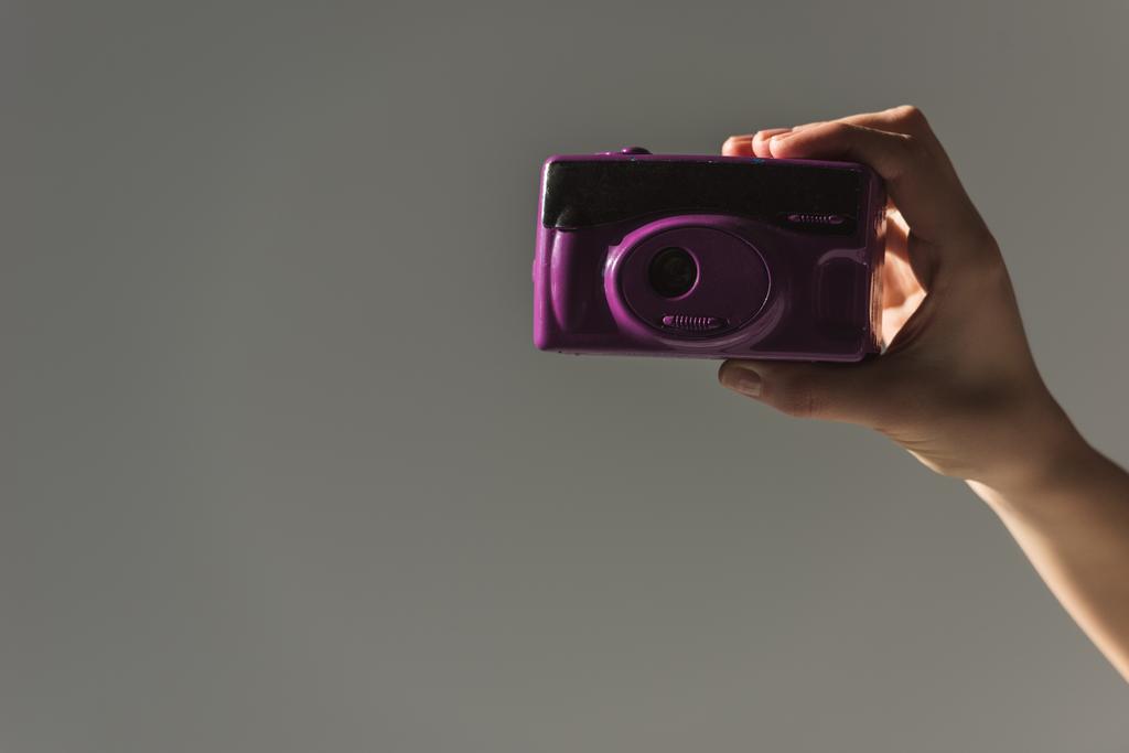 περικοπεί θέα γυναικείο χέρι που κρατά το μωβ φωτογραφική, απομονώνονται σε γκρι - Φωτογραφία, εικόνα
