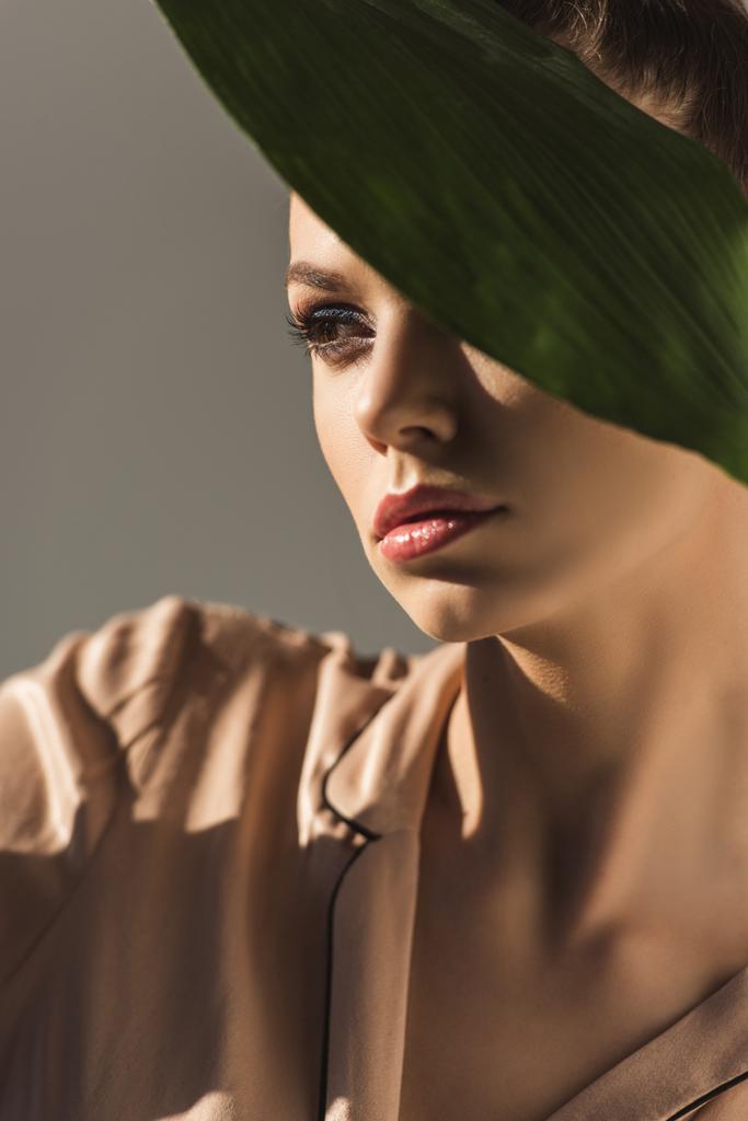 beautiful female model with green leaf, isolated on grey - Photo, Image