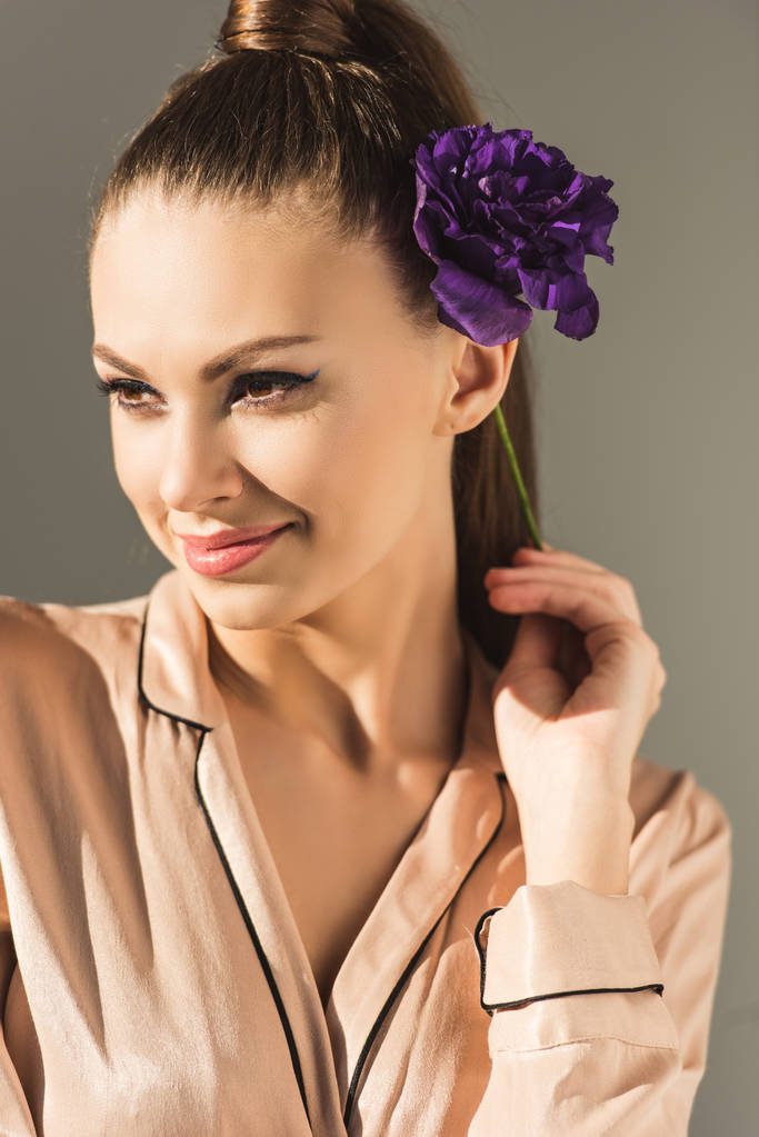 femme souriante à la mode avec fleur violette, isolée sur gris
 - Photo, image