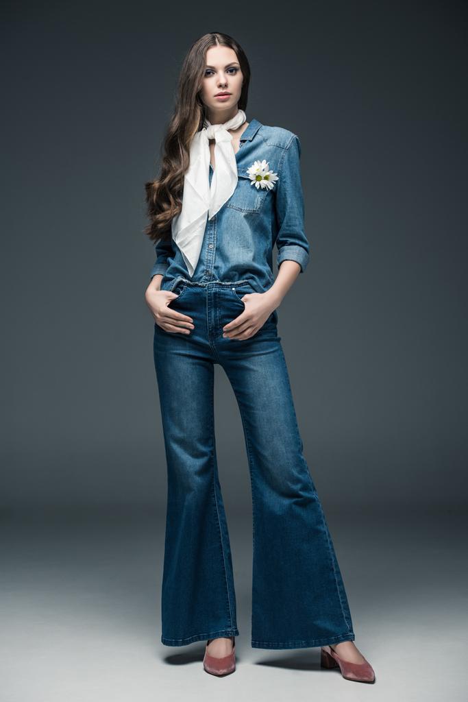 красива дівчина з довгим волоссям позує в шарфі, блискучі джинси і джинсова сорочка, на сірому
 - Фото, зображення