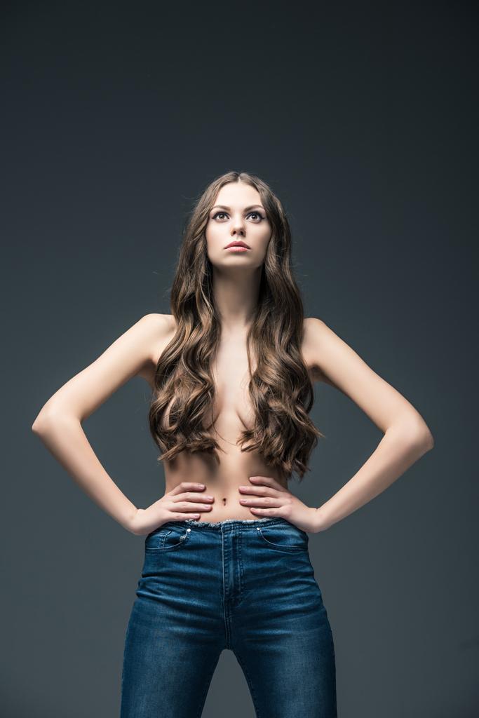 jolie fille à moitié nue avec les cheveux longs posant en jeans, isolé sur gris
 - Photo, image