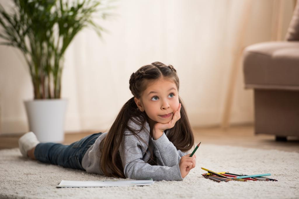 schattig kindje liggen op tapijt en tekenen met kleurpotloden - Foto, afbeelding