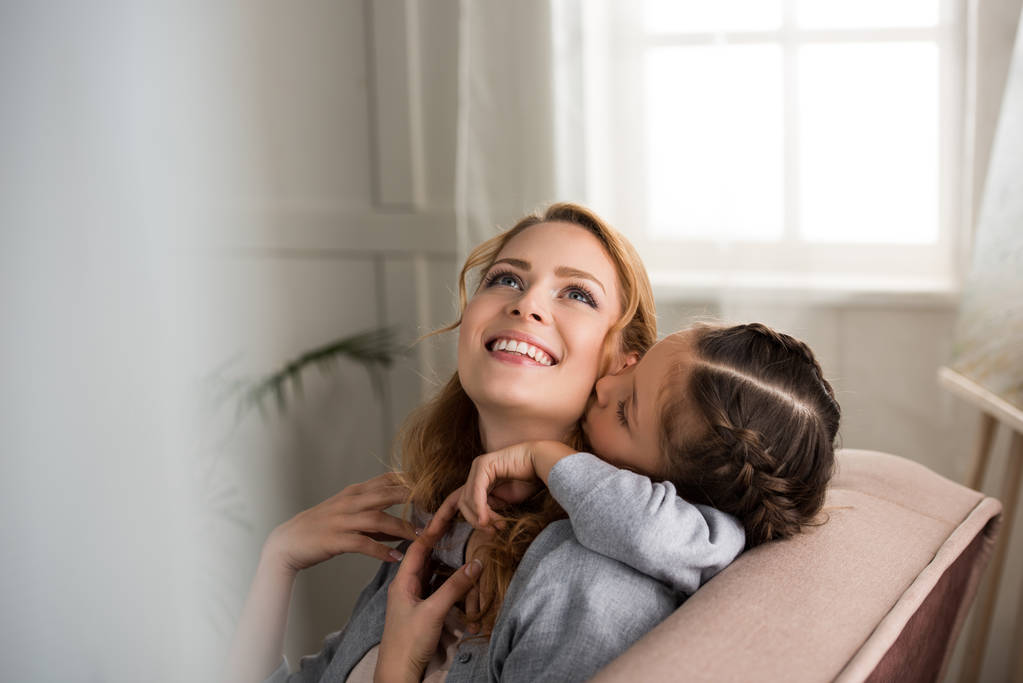 schöne glückliche Mutter und Tochter, die sich zu Hause umarmen - Foto, Bild