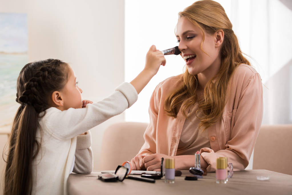 szczęśliwą matką i córeczka stosowania makijażu razem w domu - Zdjęcie, obraz