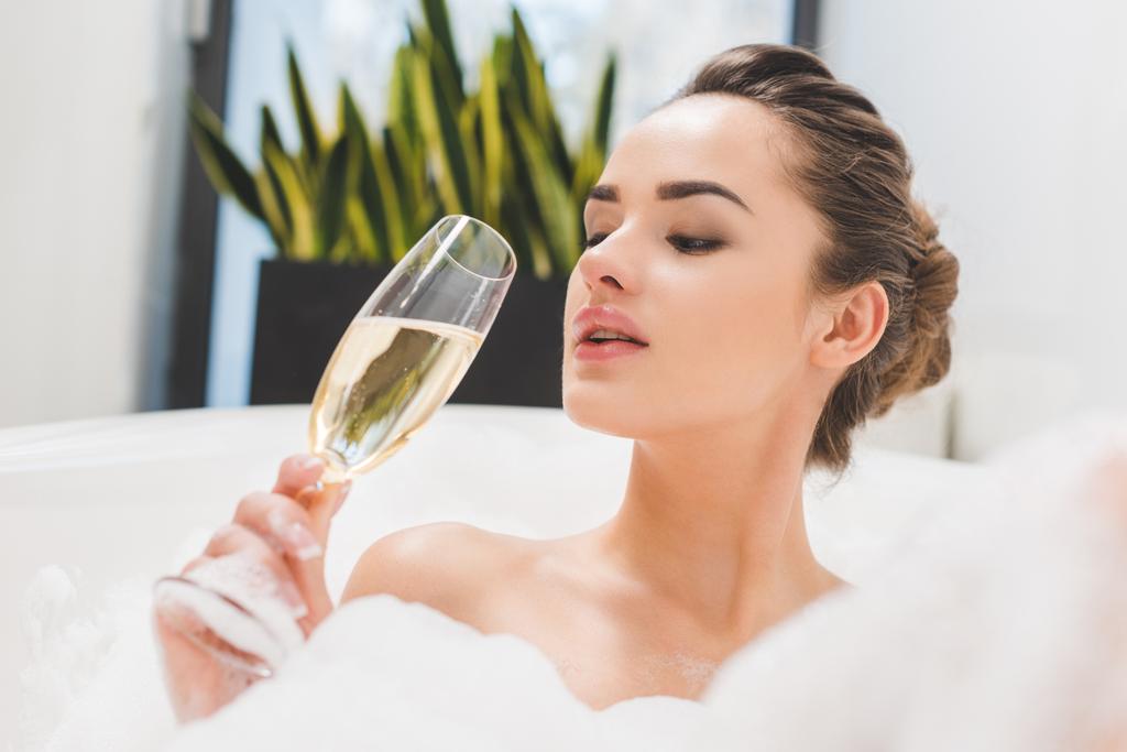 portrait of beautiful woman with glass of champagne taking bath - Photo, Image