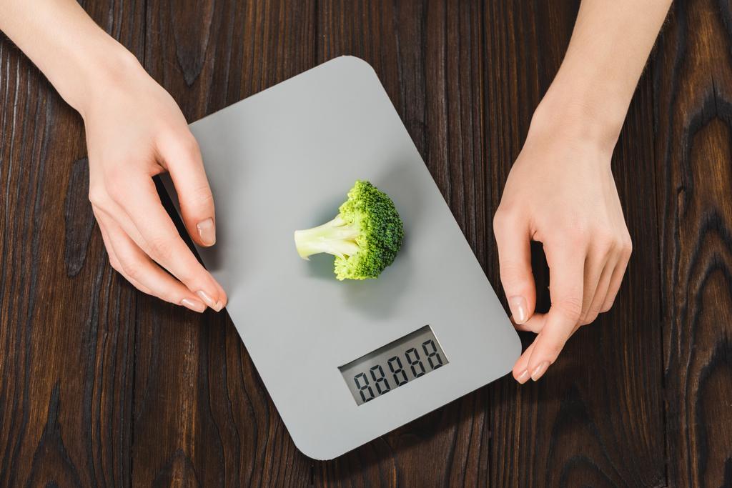 bijgesneden schot van vrouw meten gewicht van broccoli - Foto, afbeelding