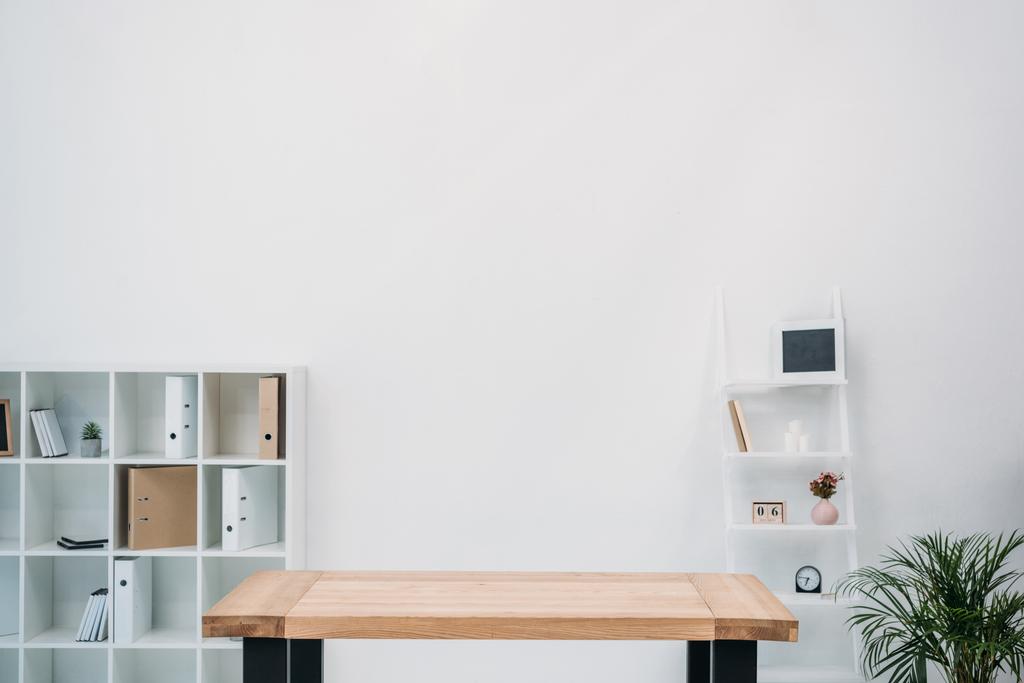 moderne Büroeinrichtung mit leerem Holztisch und Ordnern in den Regalen - Foto, Bild