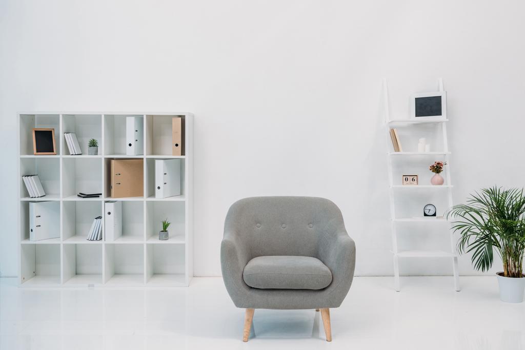 moderne kantoor interieur met grijze fauteuil en mappen op de planken - Foto, afbeelding