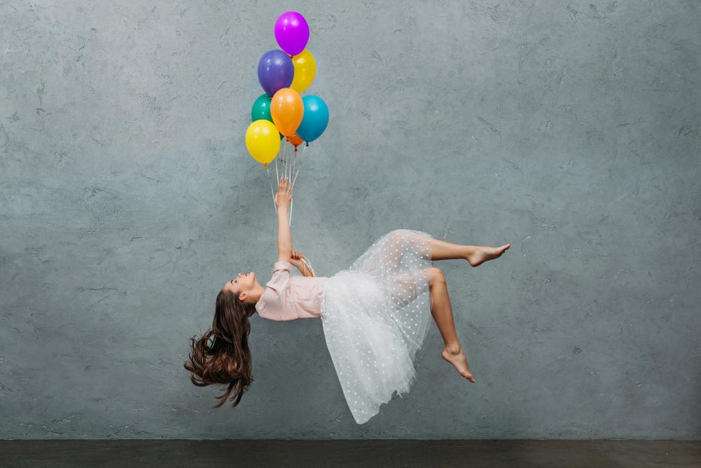 jonge vrouw zwevende met kleurrijke ballonnen - Foto, afbeelding