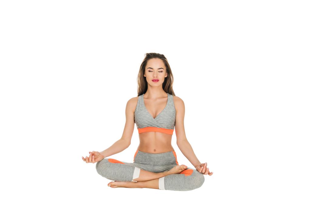 Młoda kobieta z zamkniętymi oczami medytując w pozycji lotosu na białym tle  - Zdjęcie, obraz