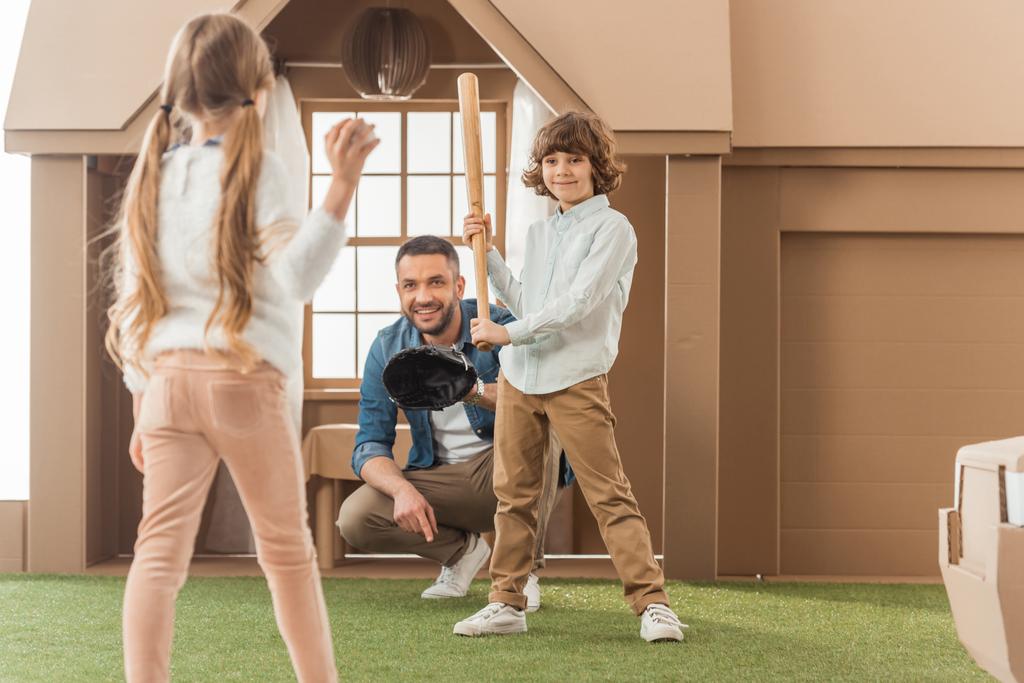 père enseignant à ses enfants comment jouer au baseball devant une maison en carton
 - Photo, image