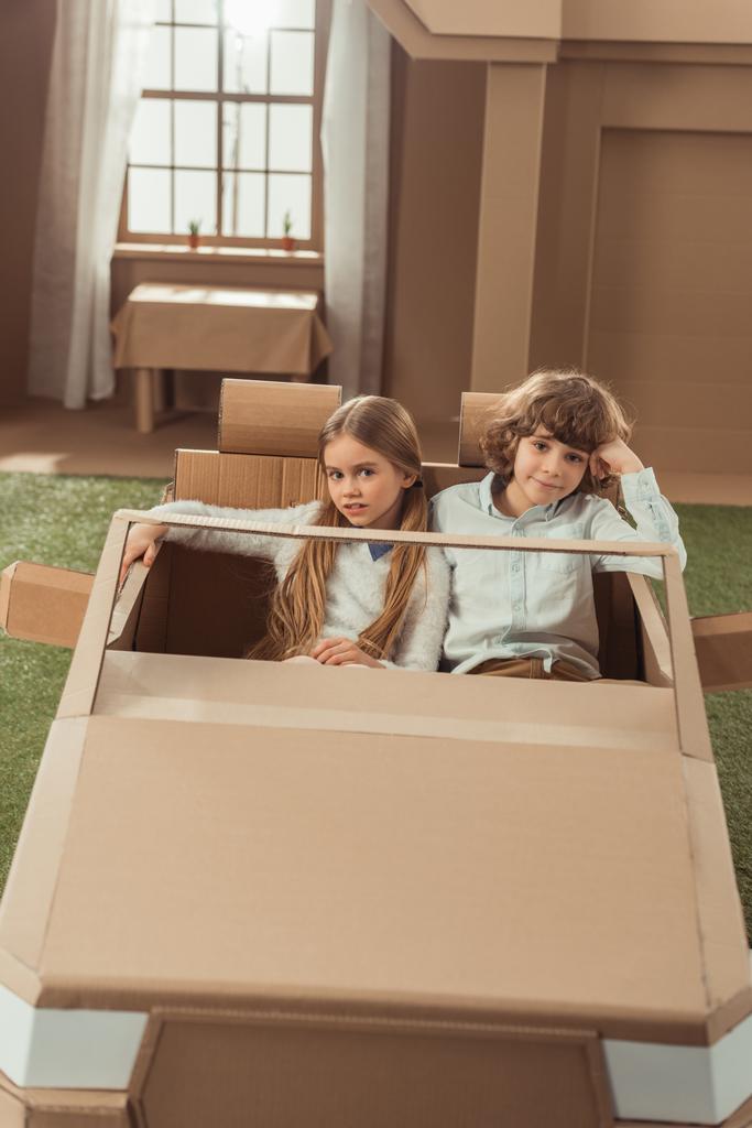 прелестные дети пара верхом на картонной машине
 - Фото, изображение