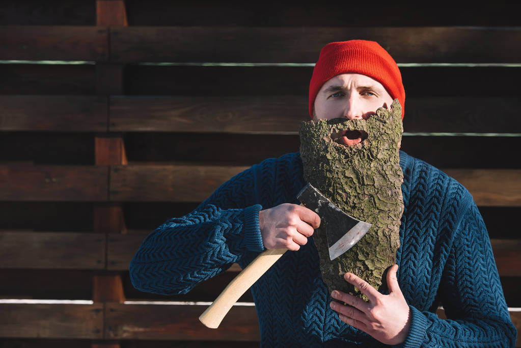 retrato de hombre con barba hecha de corteza de madera y hacha en la mano al aire libre
 - Foto, imagen
