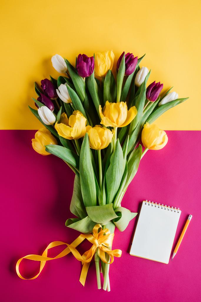 vista superior de los tulipanes de primavera con bloc de notas y lápiz para el día internacional de la mujer
 - Foto, imagen