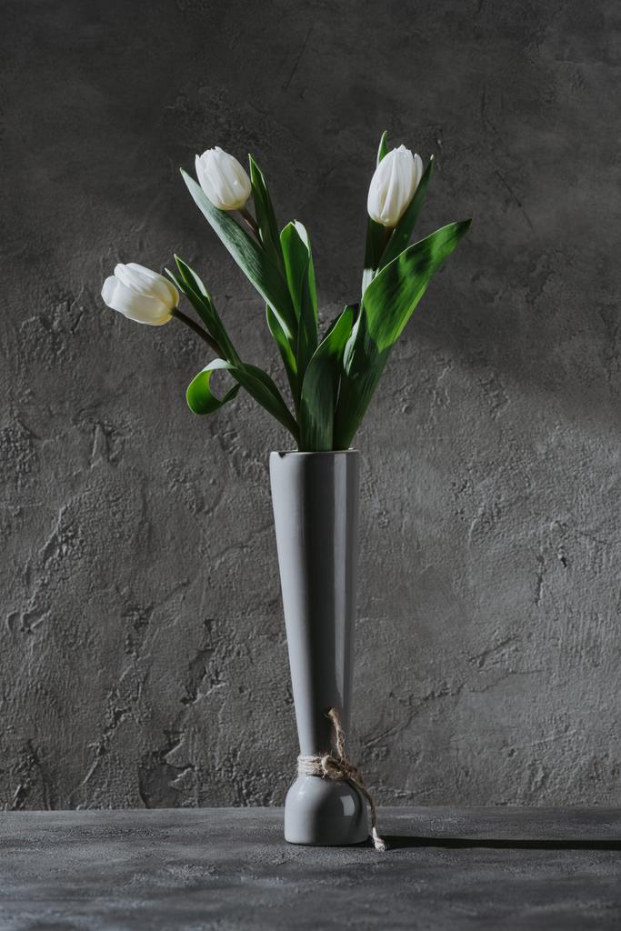 witte lente tulpen in grijze vaas op betonnen ondergrond - Foto, afbeelding