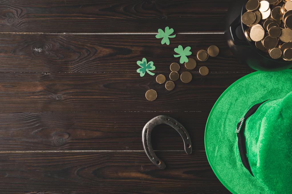 верхний вид горшок с золотыми монетами, подкова и зеленая шляпа на деревянный стол, день святого Патрика концепции
 - Фото, изображение