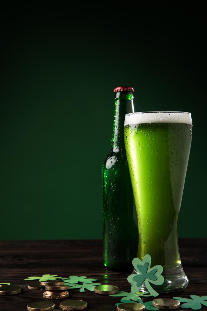 skleněné láhve a sklo zelené pivo s mincemi na stole, st patricks day koncept - Fotografie, Obrázek