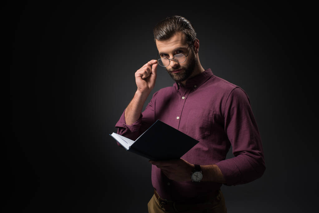 πορτρέτο του επιχειρηματία σε γυαλιά με notebook που απομονώνονται σε μαύρο - Φωτογραφία, εικόνα