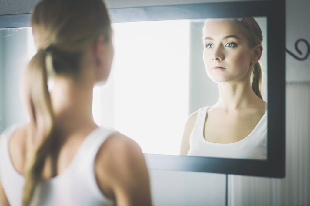 πρόσωπο της νεαρής όμορφης υγιούς γυναίκας και αντανάκλαση στον καθρέφτη - Φωτογραφία, εικόνα