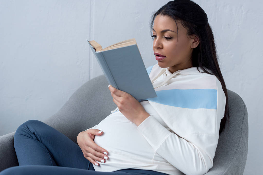 african american Kobieta w ciąży, czytanie książki w domu - Zdjęcie, obraz