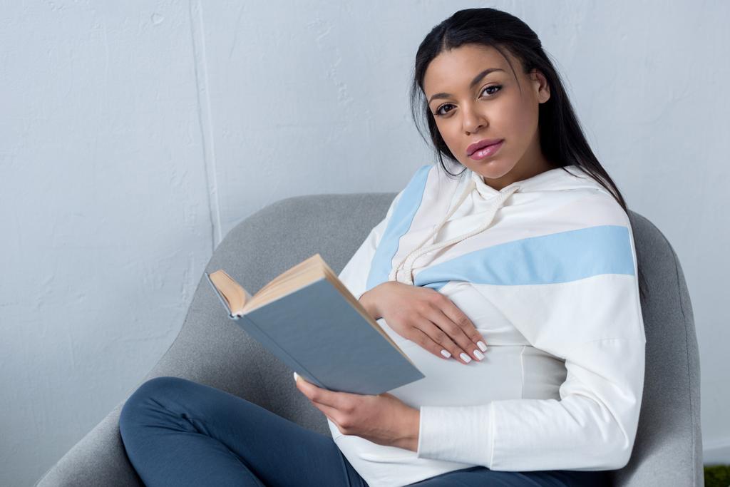 african american pregnant woman holding book and looking at camera - Photo, Image