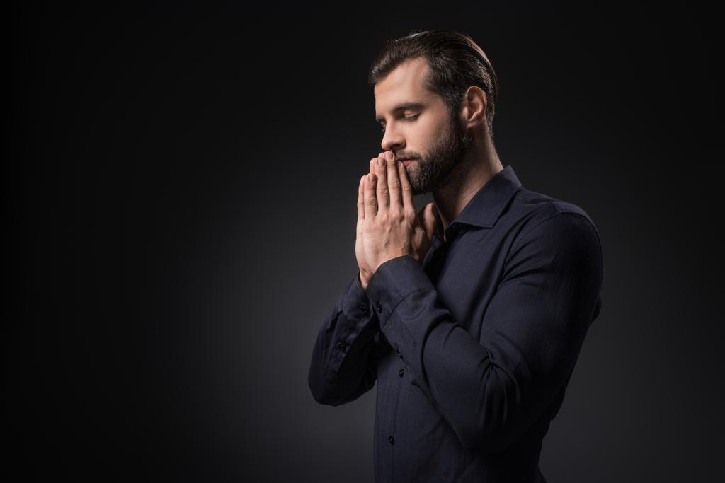 side view of man praying isolated on black - Photo, Image