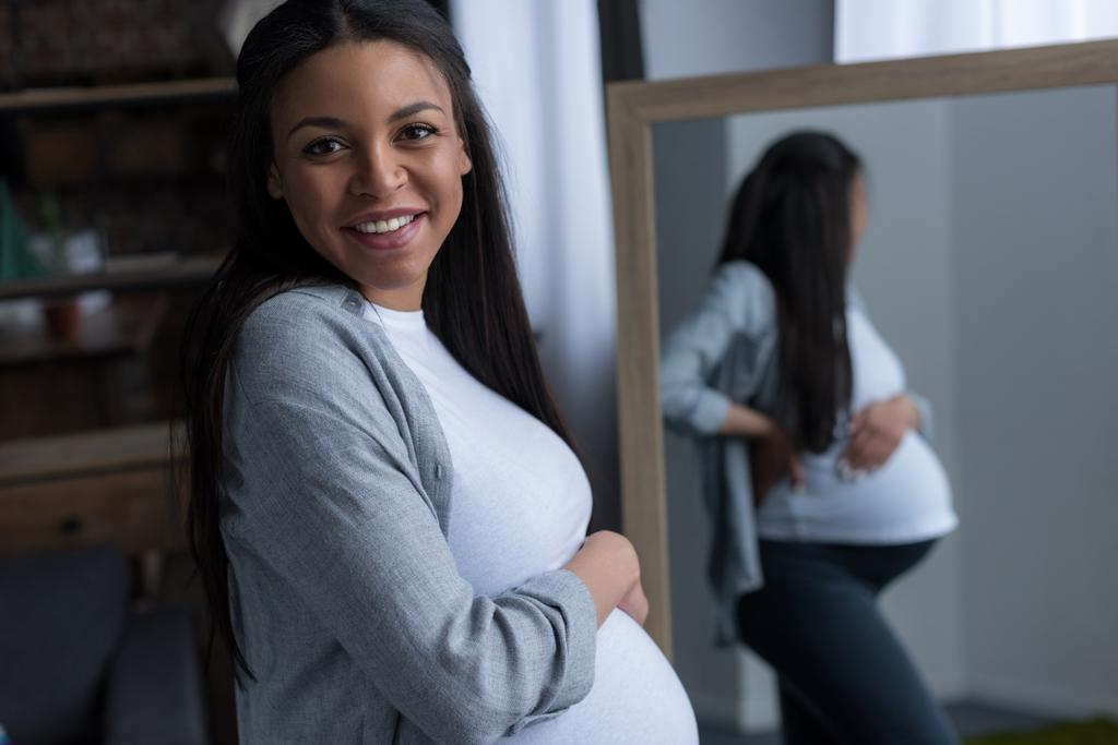 ayna duran neşeli Afro-Amerikan hamile kadın - Fotoğraf, Görsel