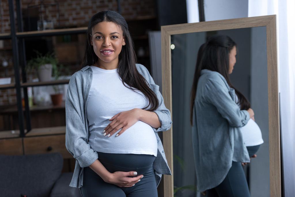 Αφρικανική αμερικανική έγκυος γυναίκα με μεγάλη κοιλιά μπροστά σε καθρέφτη - Φωτογραφία, εικόνα