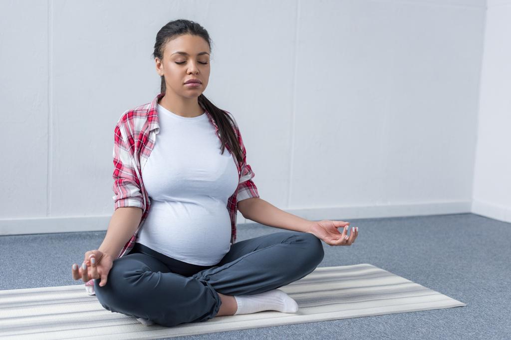 mujer embarazada afroamericana practicando yoga en la estera
 - Foto, imagen