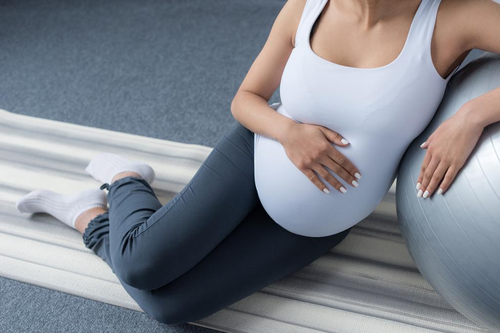 bijgesneden weergave van zwangere vrouw zit met fit-bal - Foto, afbeelding