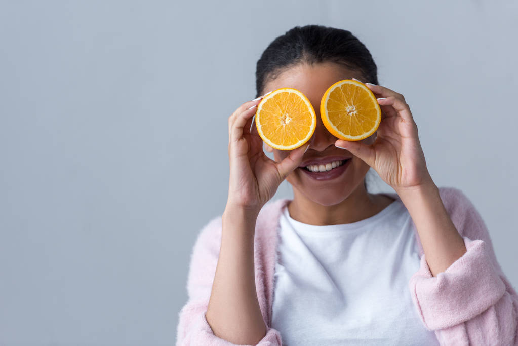 alegre afroamericana chica con mitades de naranja, aislado en gris
 - Foto, imagen