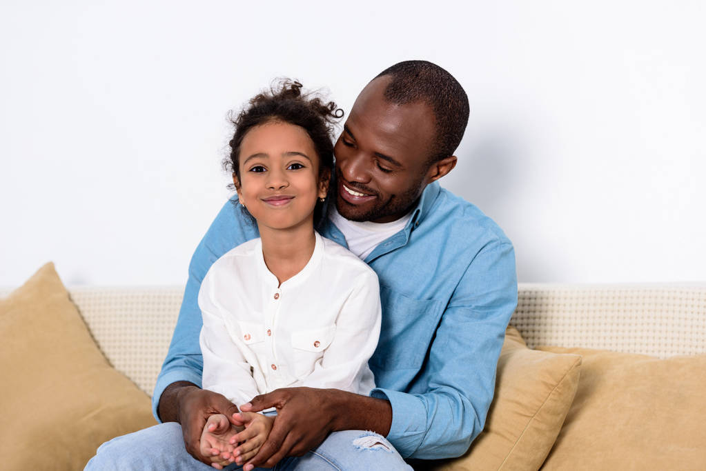 happy african american father and daughter on sofa at home - Photo, Image