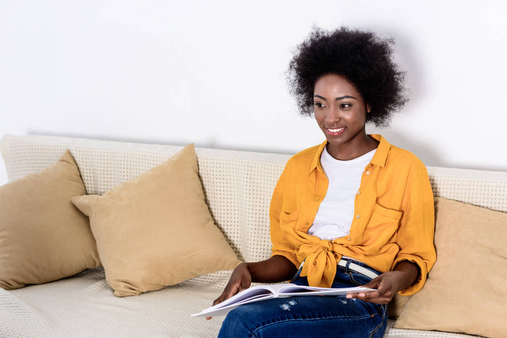mujer afroamericana sosteniendo libro y mirando a casa
 - Foto, imagen