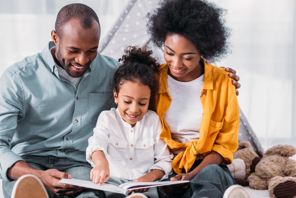 glücklich afrikanisch-amerikanische Tochter liest für Eltern zu Hause - Foto, Bild