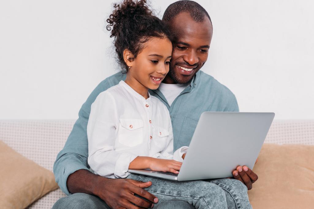 feliz pai e filha afro-americanos usando laptop em casa
 - Foto, Imagem
