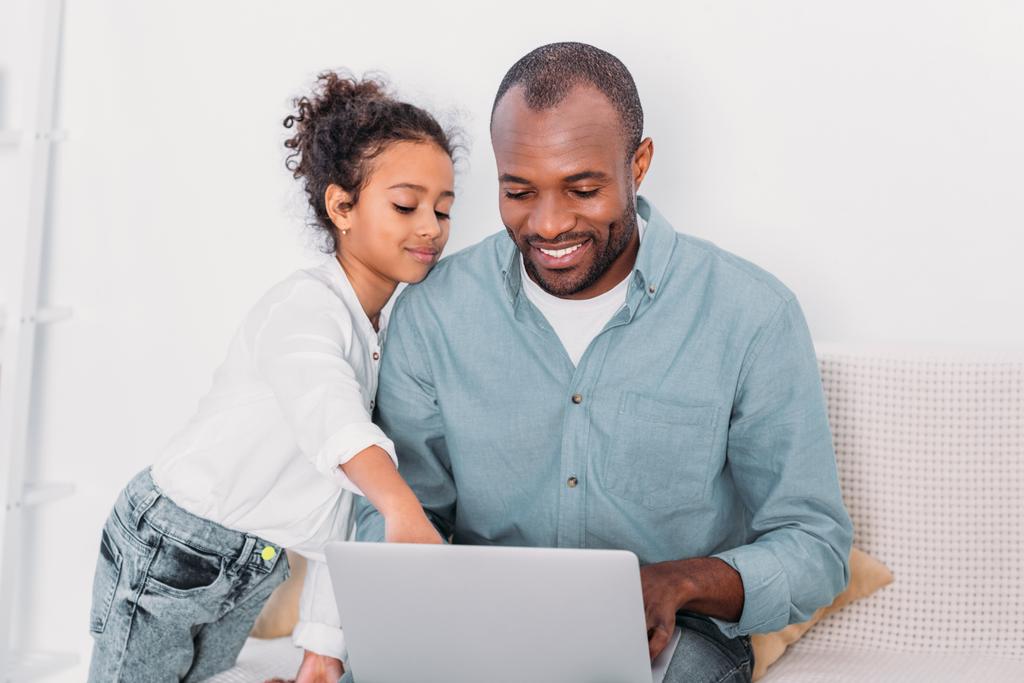 african american daughter showing something on laptop to father at home - Photo, Image