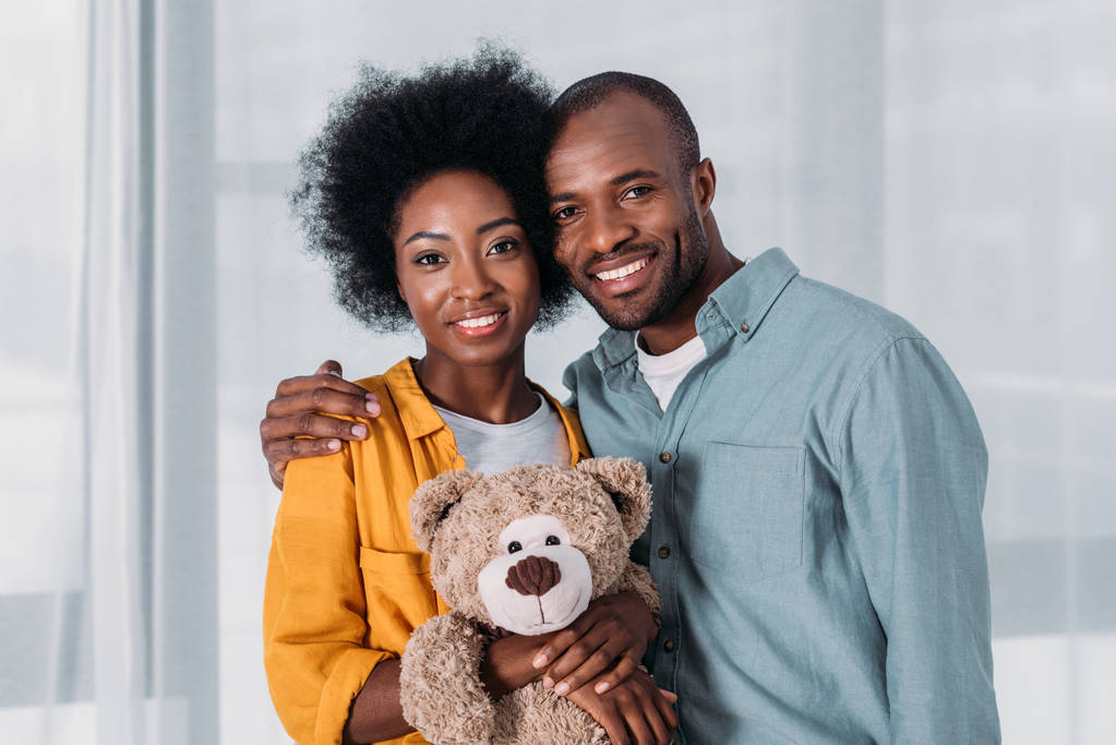 glückliches afrikanisch-amerikanisches Paar mit Teddybär zu Hause - Foto, Bild