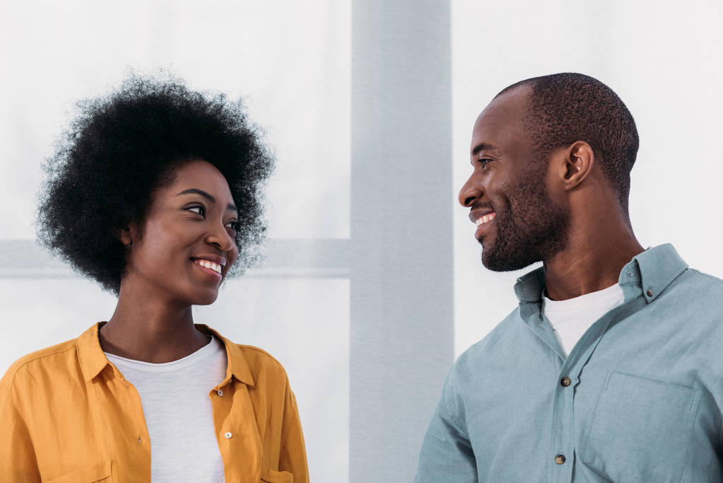 lachende Afrikaanse Amerikaanse echtpaar kijken elkaar thuis - Foto, afbeelding