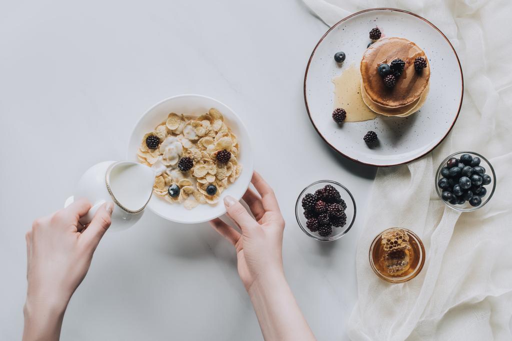 vue du dessus de la personne versant du lait dans un bol avec muesli pendant le petit déjeuner
 - Photo, image