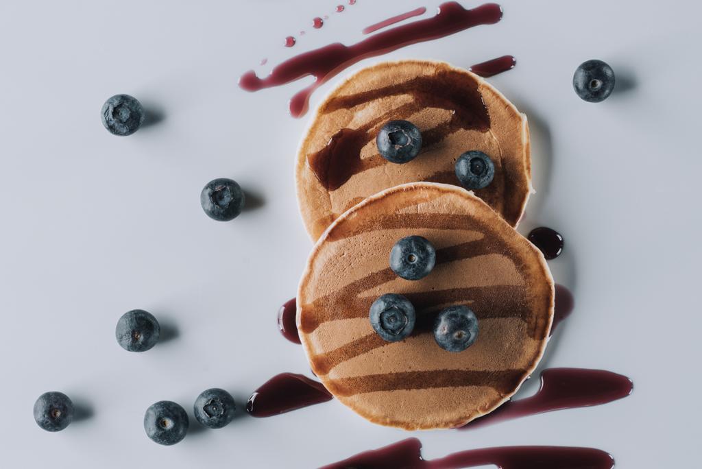 Blick von oben auf leckere süße hausgemachte Pfannkuchen mit frischen Blaubeeren und Marmelade auf grau    - Foto, Bild