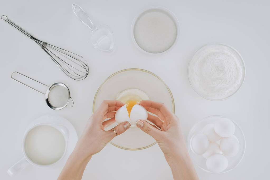グレーに分離されたパンケーキを調理しながら卵を保持している人のクロップ撮影 - 写真・画像