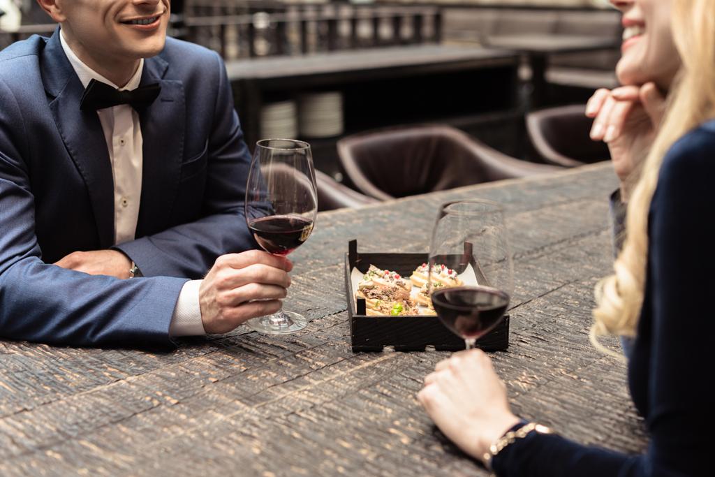 περικοπεί shot του ευτυχισμένο ζευγάρι ενηλίκων πίνει κρασί στο εστιατόριο - Φωτογραφία, εικόνα