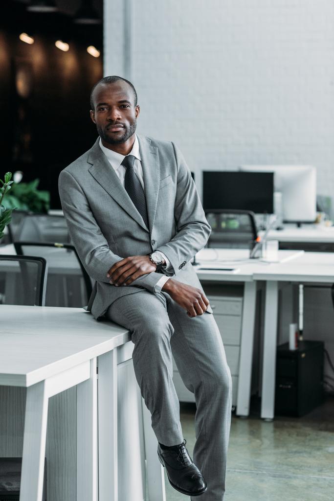 Afro-Amerikaanse zakenman zittend op tafel in kantoor - Foto, afbeelding