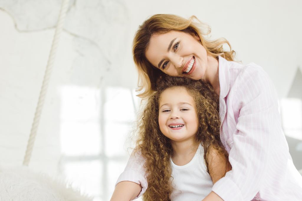 cheerful mother and adorable daughter looking at camera - Photo, Image