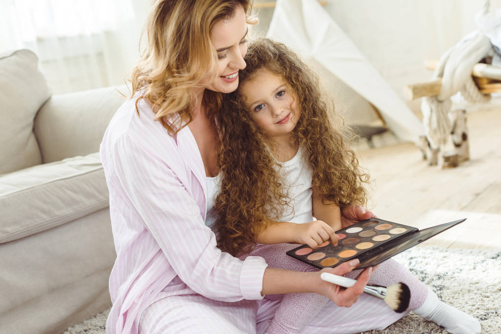 mãe ensinando sua filha a aplicar maquiagem
 - Foto, Imagem