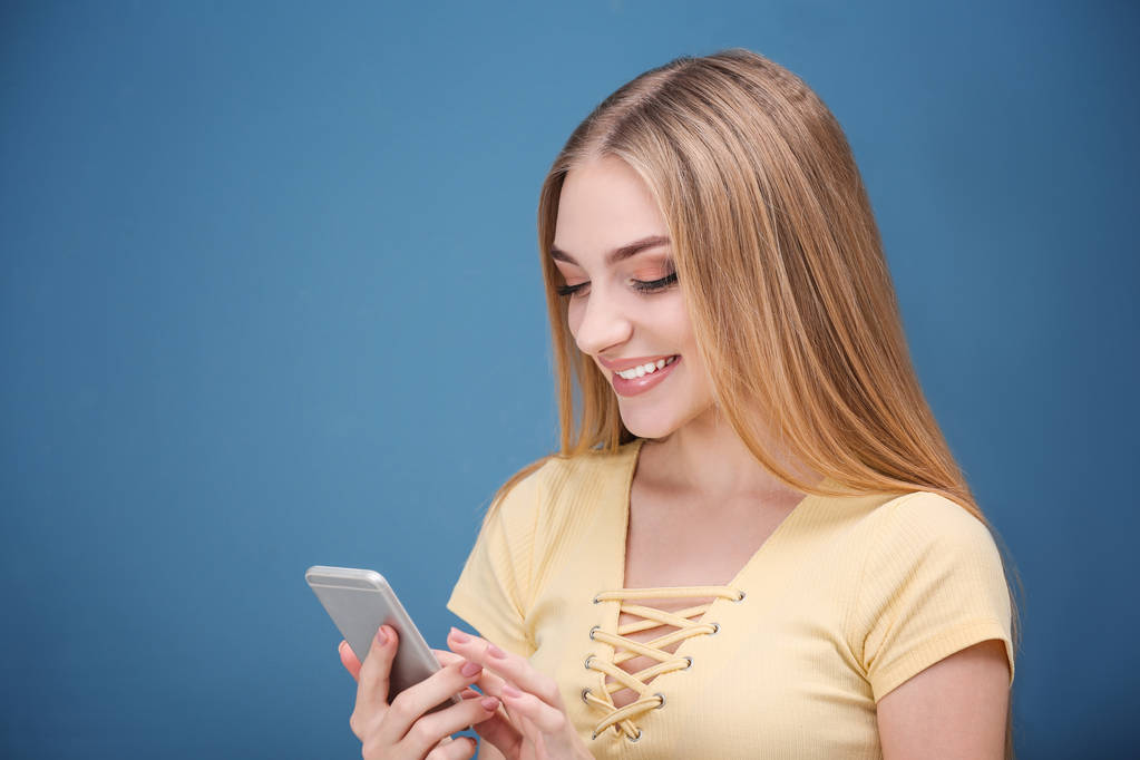 Молодая женщина с мобильным телефоном на цветном фоне
 - Фото, изображение