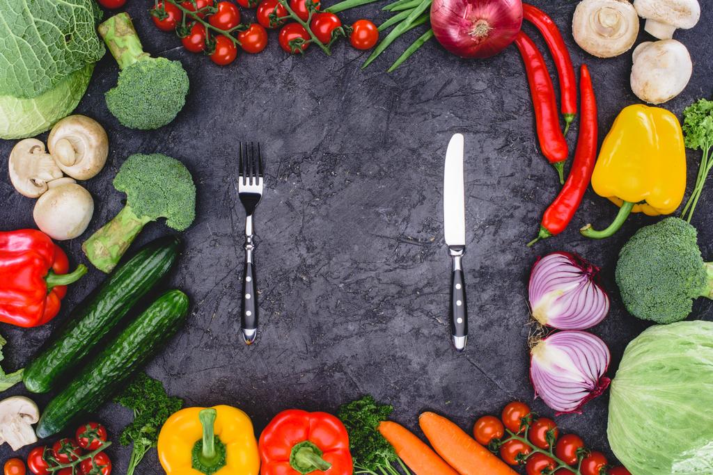 pohled shora čerstvé organické různé zeleniny a vidlice s nožem na černém pozadí - Fotografie, Obrázek