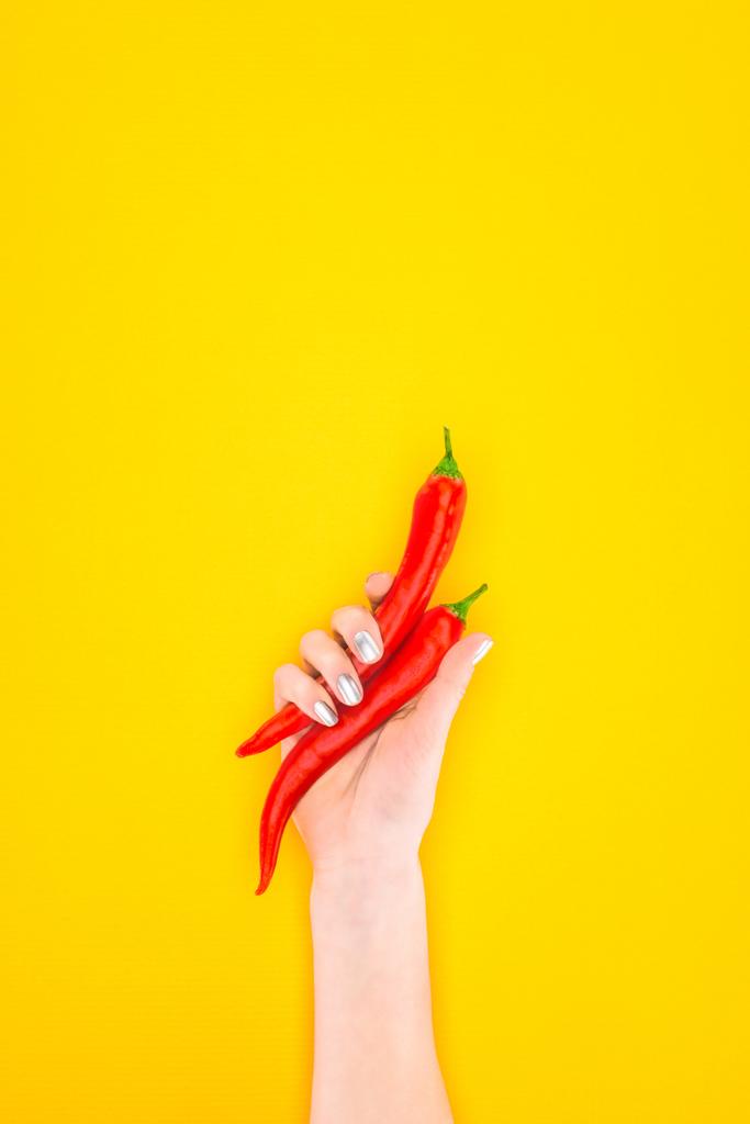 cropped shot of person holding raw red chilli peppers in hand isolated on yellow - Photo, Image