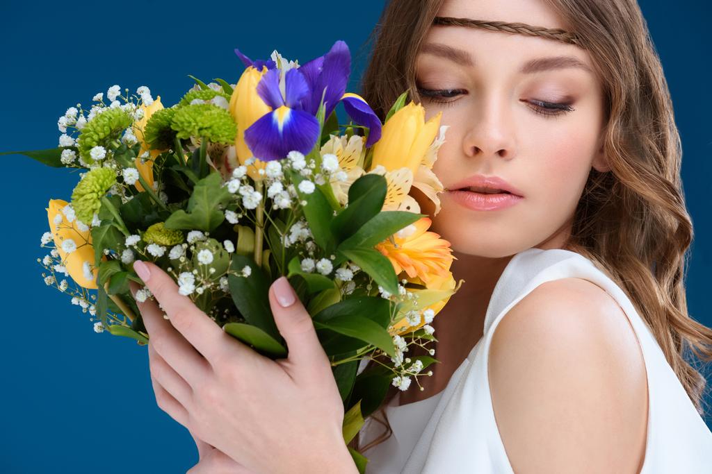 όμορφη νεαρή γυναίκα κρατώντας floral ανθοδέσμη που απομονώνονται σε μπλε - Φωτογραφία, εικόνα