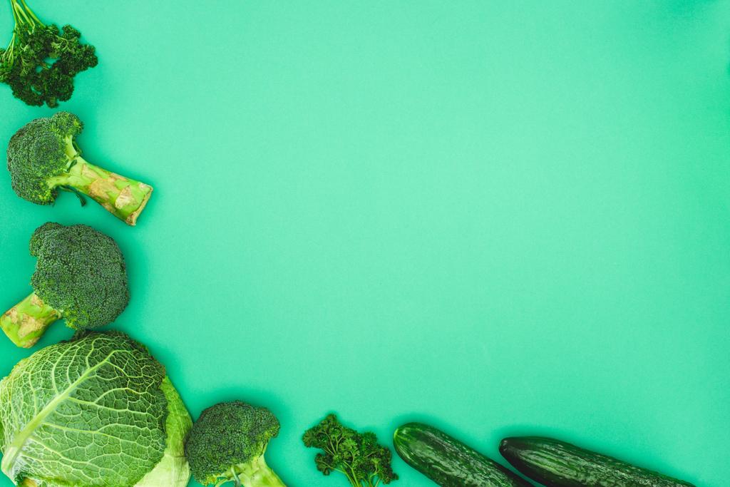 Draufsicht auf frischen rohen Brokkoli, Petersilie, Gurken und Wirsing isoliert auf grünem Hintergrund - Foto, Bild